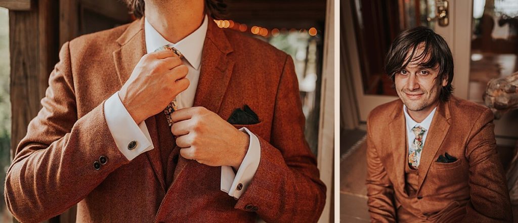 Boho groom in a rust colored twill suit with a floral tie and black pocket square