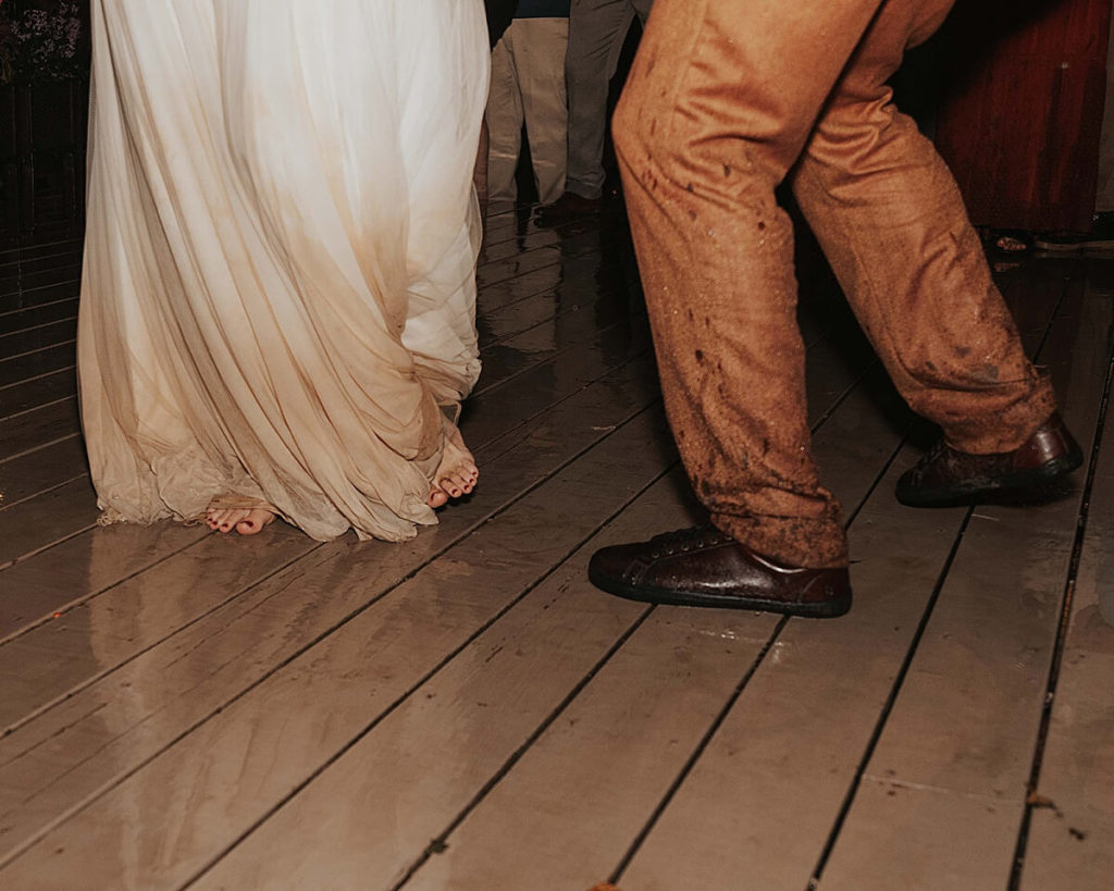 Boho bride and groom dancing barefoot in the rain