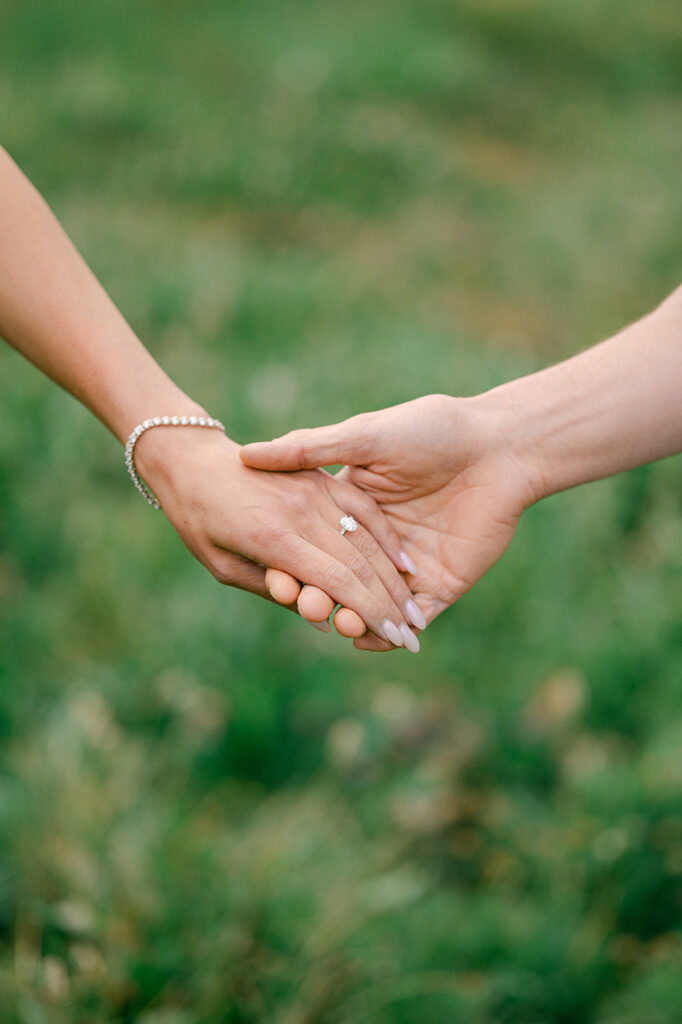 Couple holds hands and shows their engagement ring in Lake Tahoe.