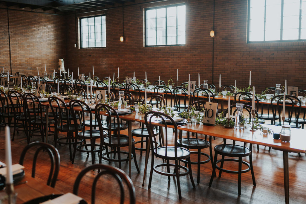 Elegant wedding reception at the Common House with long tables, candles, greenery and black accents.