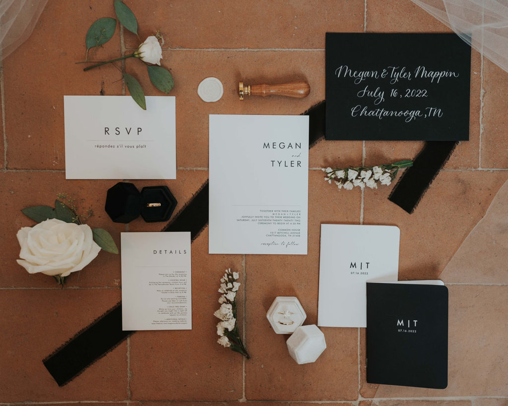Styled flat lay photo featuring black and white wedding stationery and vow books.