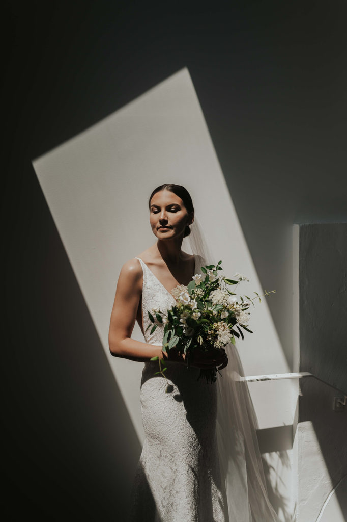 Tennessee bride holding a simple greenery bouquet standing in direct indoor light.