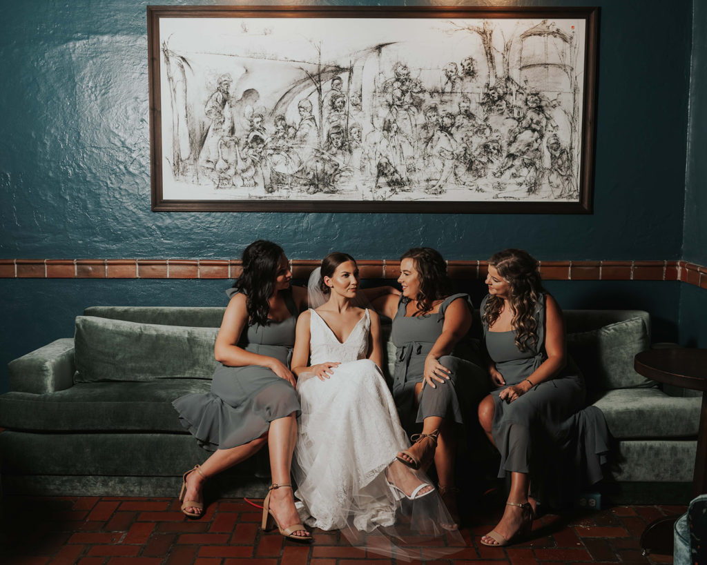 Bride and bridesmaids sitting on a blue velvet couch at the Common House in Chattanooga, TN.