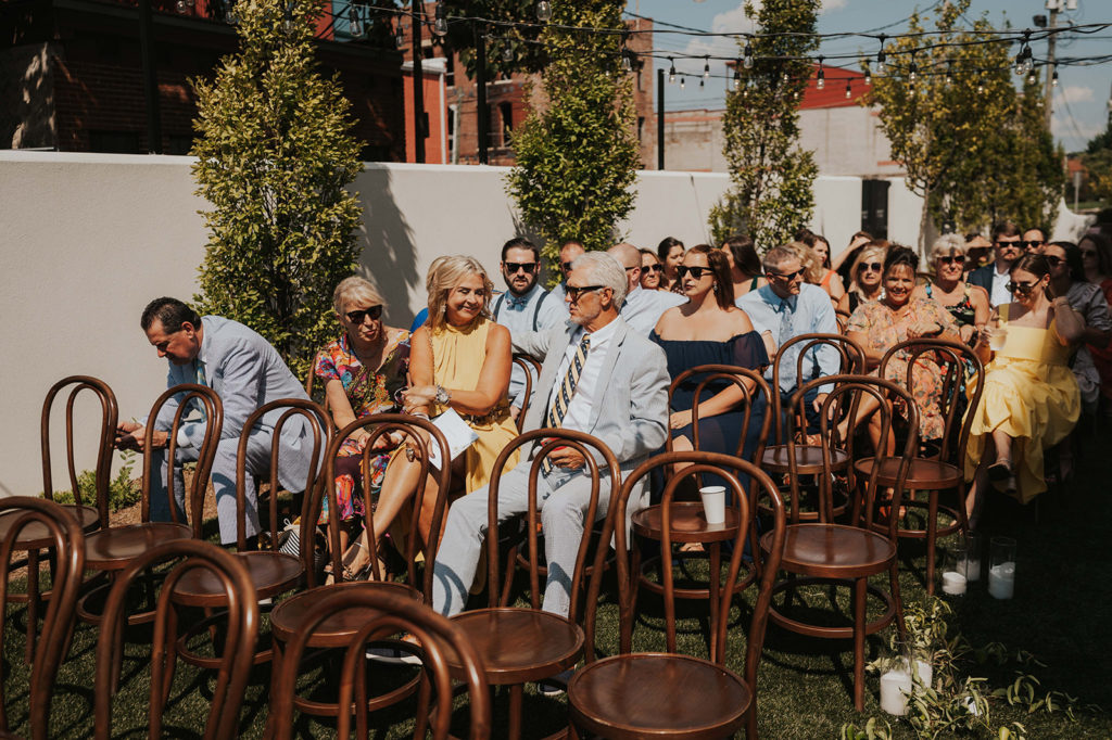 Outdoor summer wedding ceremony with brown chairs at the Common House courtyard in Chattanooga, TN.