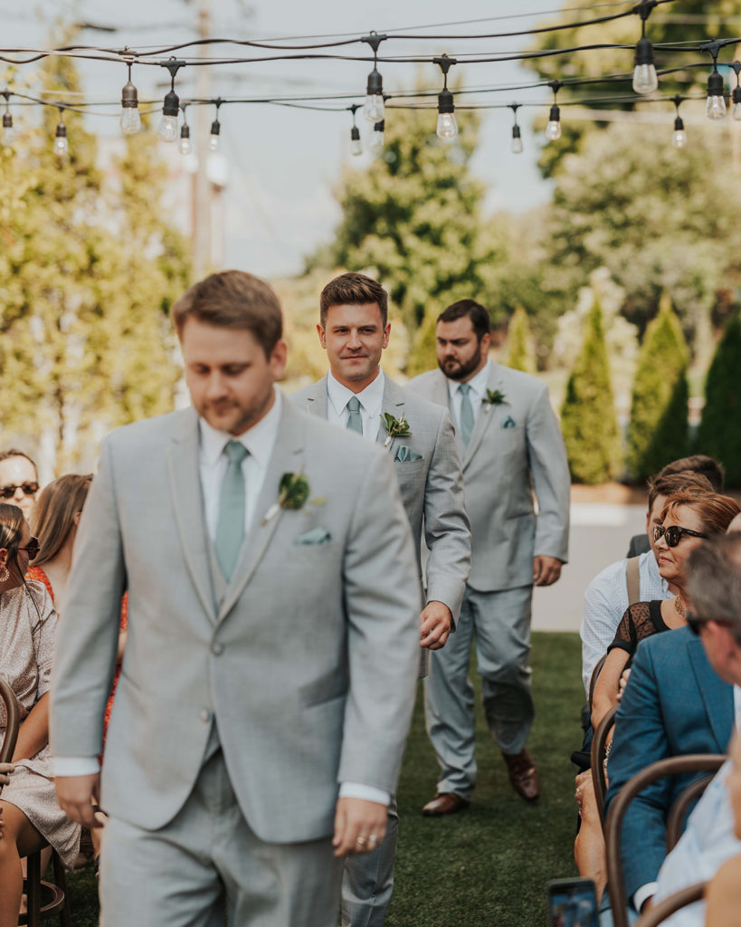 Groomsmen walking down the aisle at this outdoor ceremony at the Common House in Chattanooga, TN.
