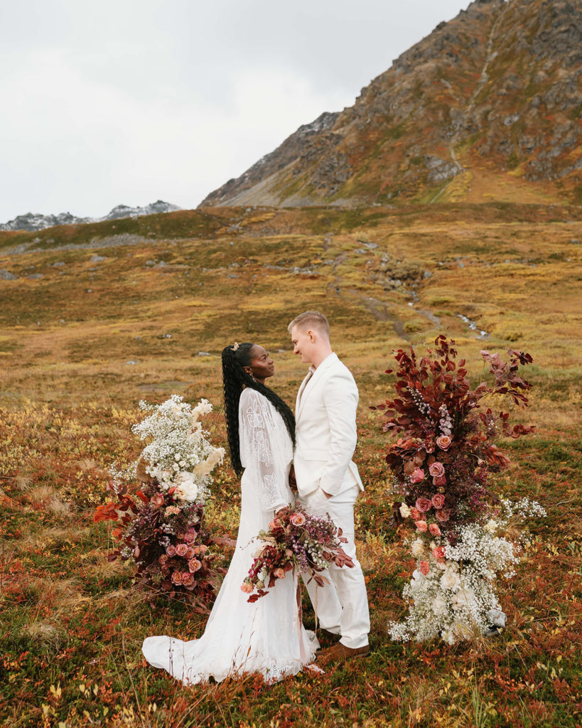 Elegant wedding ceremony in Alaska with standing floral installation arch.
