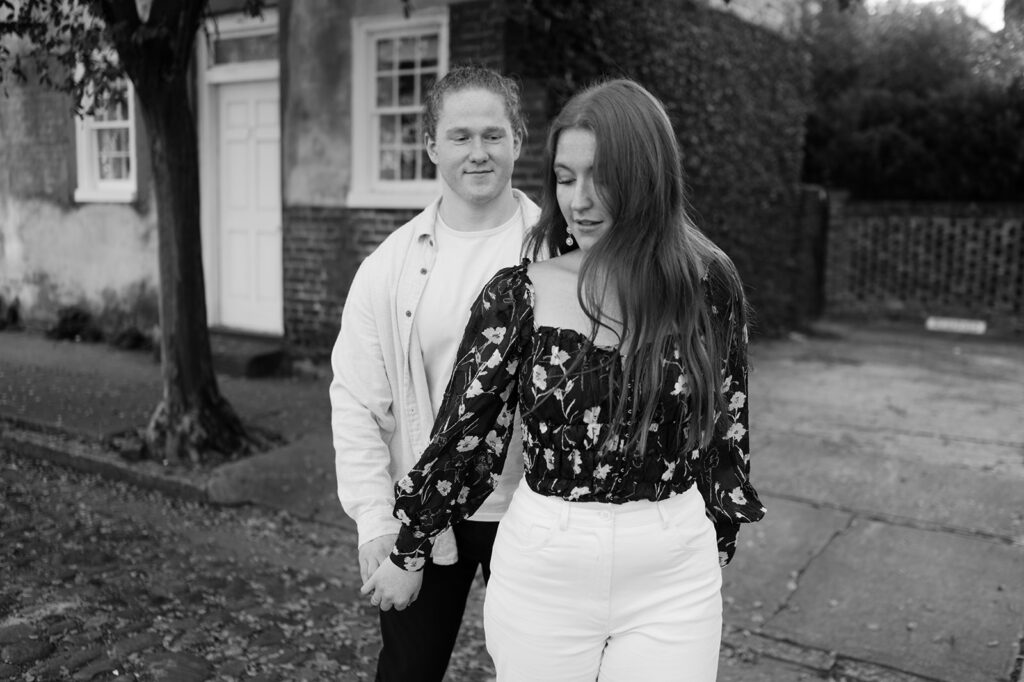 Couple holds hands in the downtown streets of Charleston, SC during their engagement photos.