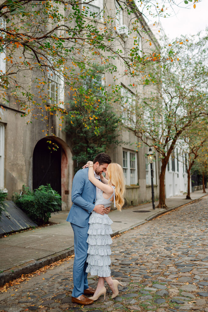 Husband and wife hug on the streets of Charleston during their engagement photos by Sarah Woods.