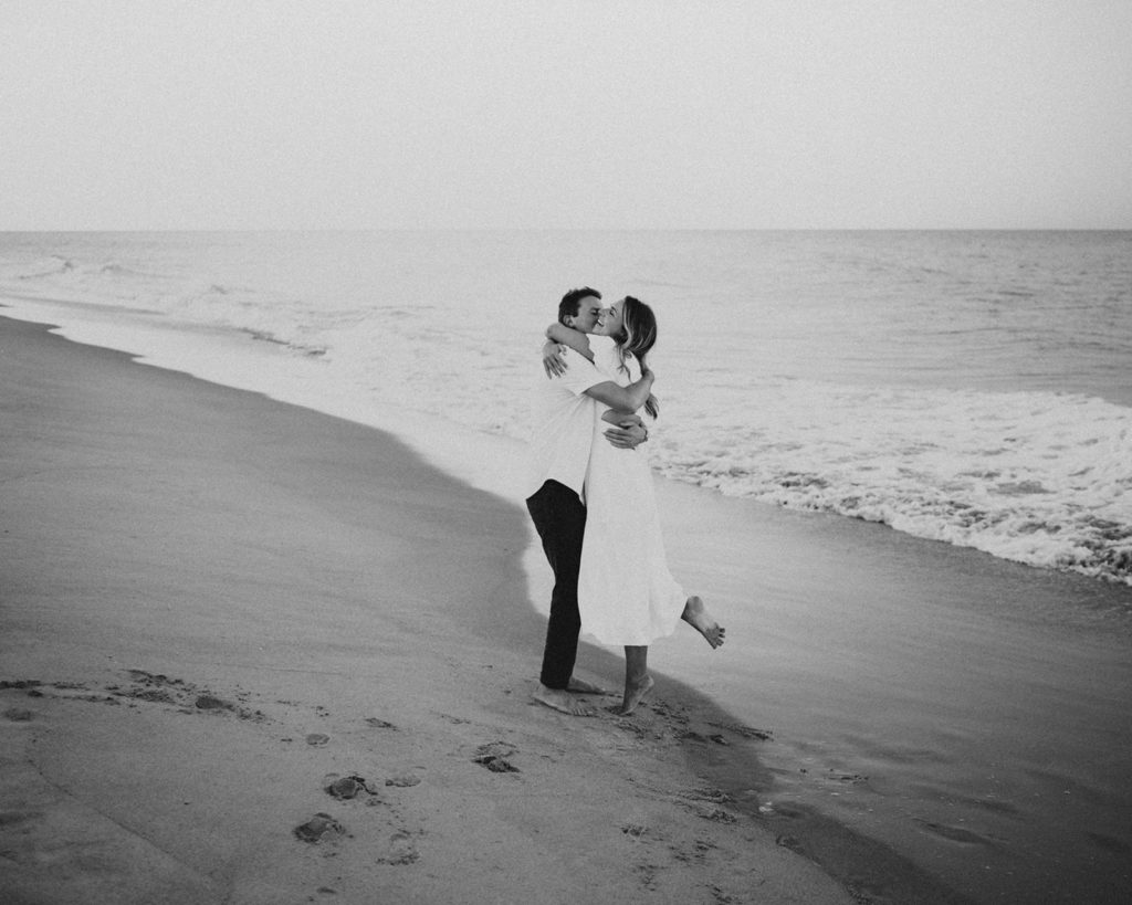 Woman and man hug each other on a Florida beach during their beach engagement photographs