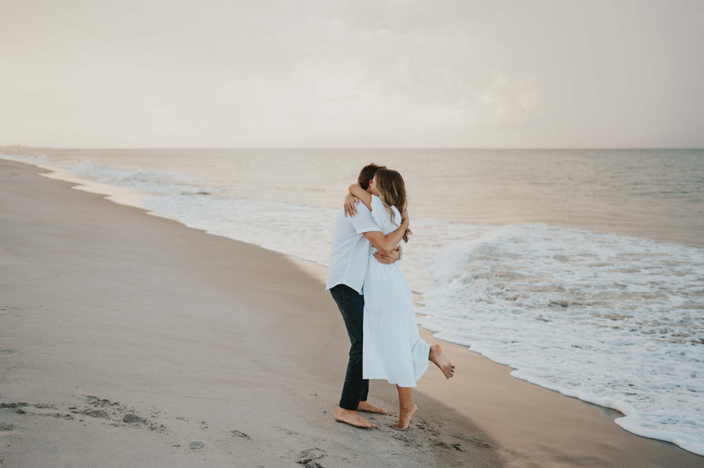 Man and Woman hug each other during their beach engagement photographs