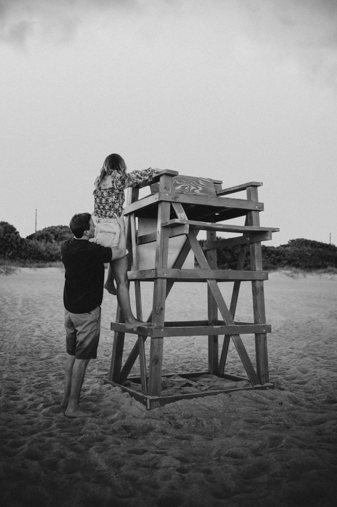 Man helps his fiancé down from the lifeguard tower