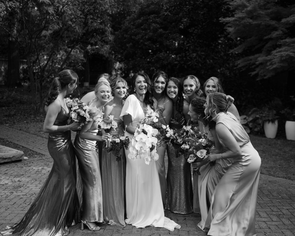 Bridesmaids lean in towards each other and laugh