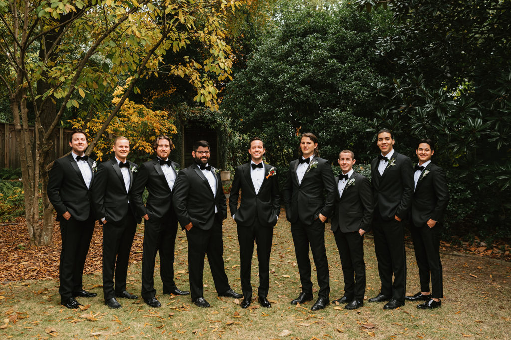 Groomsmen stand in a line and smile