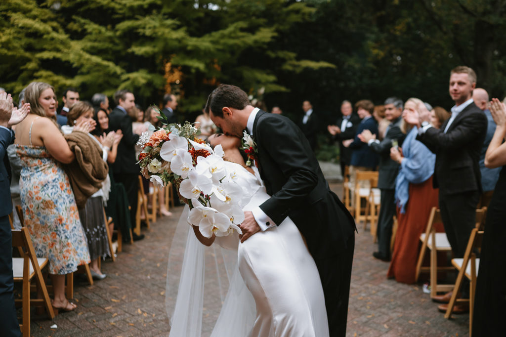 Bride and Groom kiss at the end of wedding aisle 