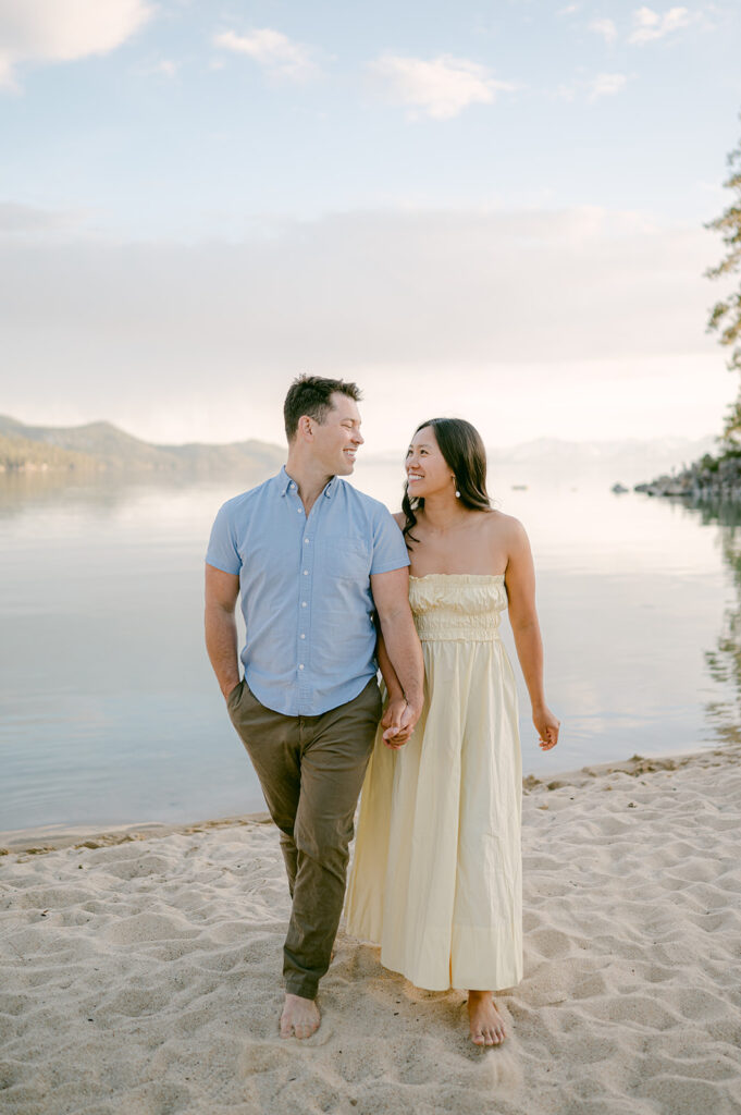 Couple walks on Sand Harbor beach during engagement photo session.