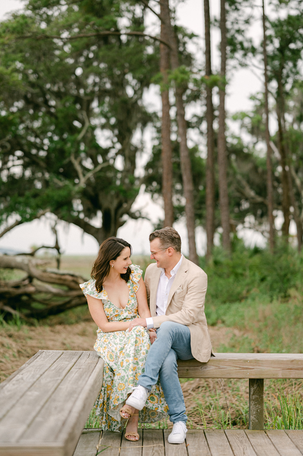 Couple laughing on a wooden bench near a river marsh in Palmetto Bluff, Bluffton, South Carolina. 