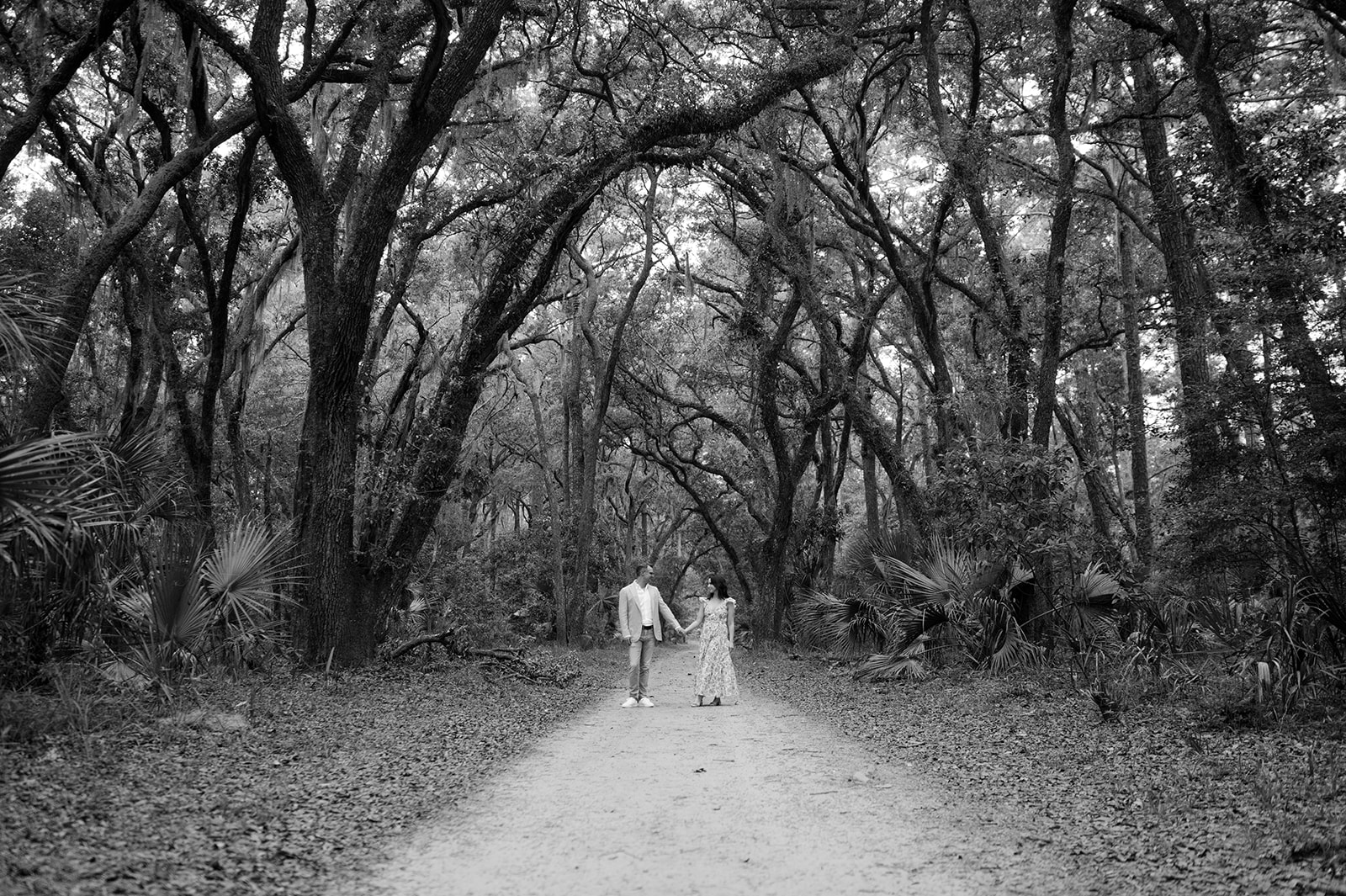 Black and white documentary style couple portrait in Palmetto Bluff under large oak trees. 