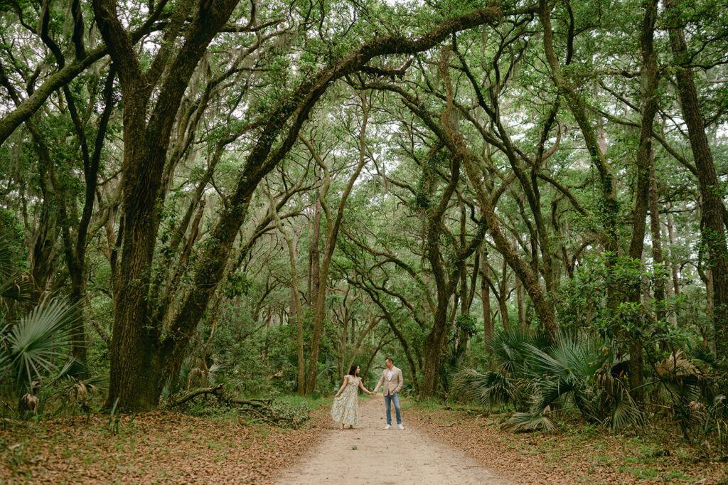 Couple holding hands during their photoshoot under Live Oak trees in Palmetto Bluff, Bluffton, South Carolina. 