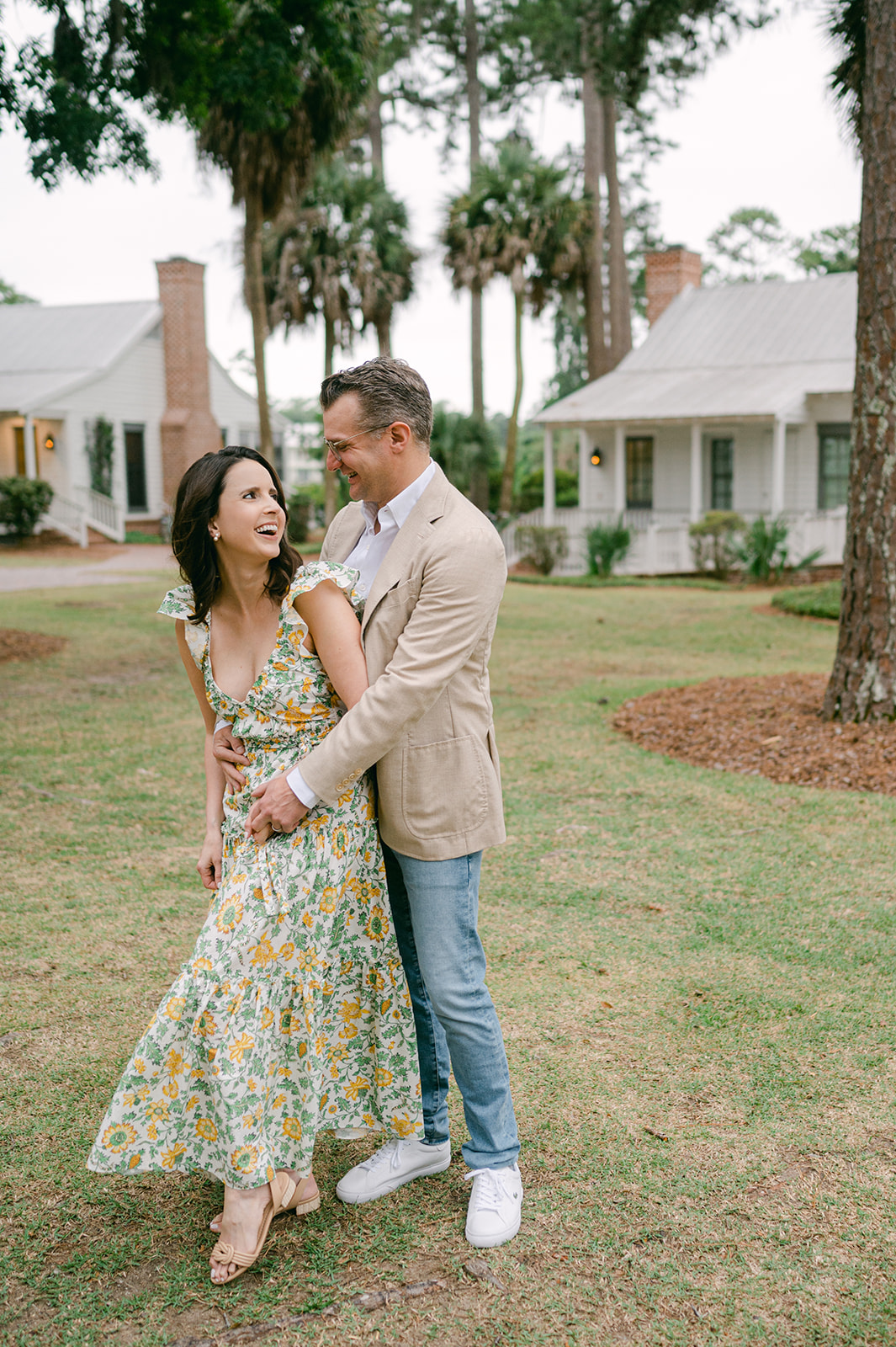 Candid couple embracing in front of a white cottage at Palmetto Bluff. 
