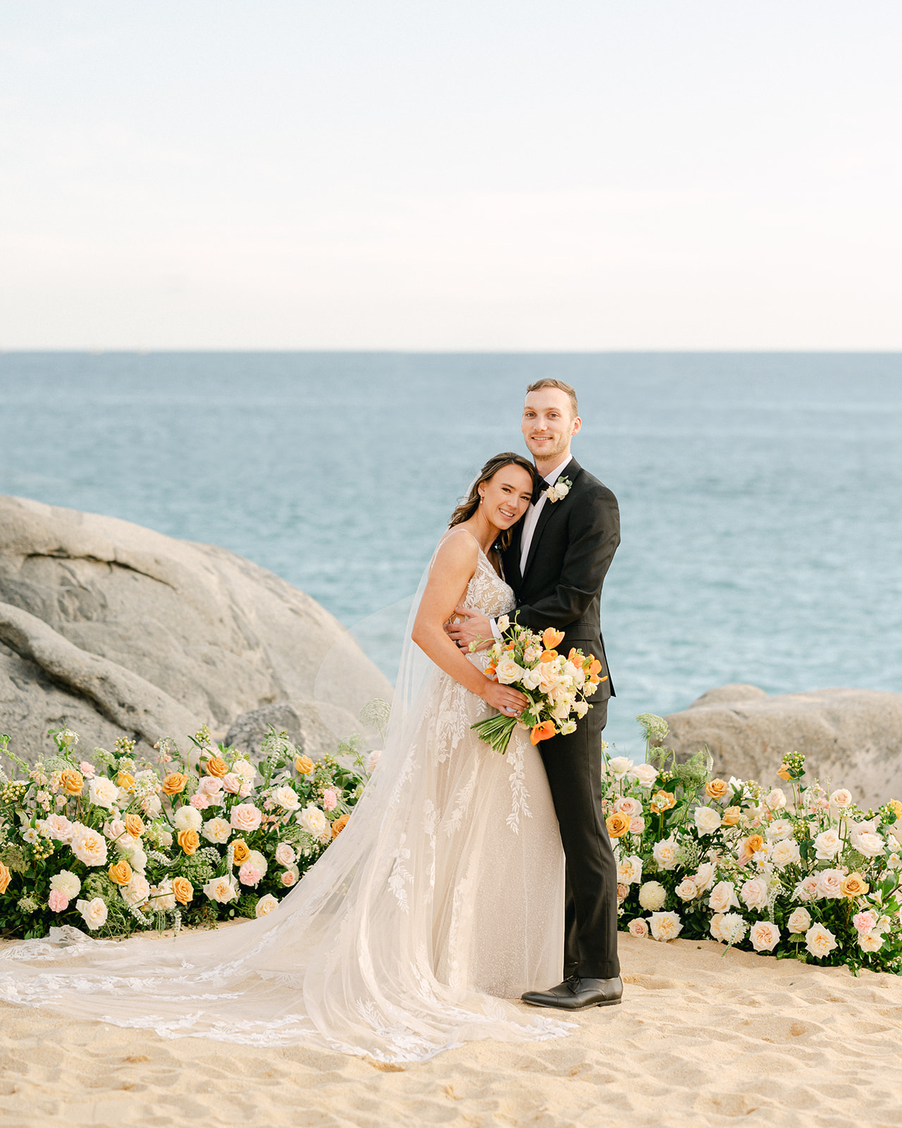 Wedding weekend in Cabo bride and groom portrait on the beach with a grounded floral arch. 