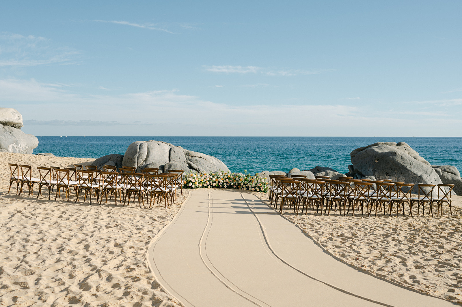 Intimate beach wedding ceremony in Cabo San Lucas, Mexico with a grounded floral arch. 