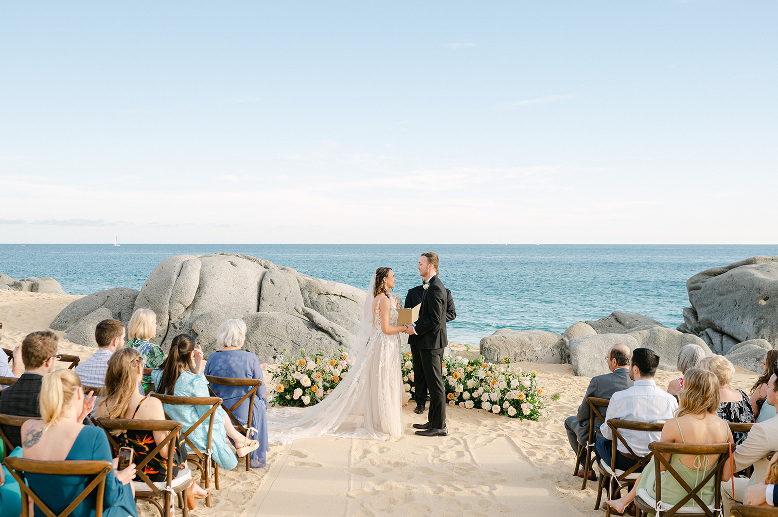 Romantic beach wedding ceremony in Cabo San Lucas with a grounded floral arch. 