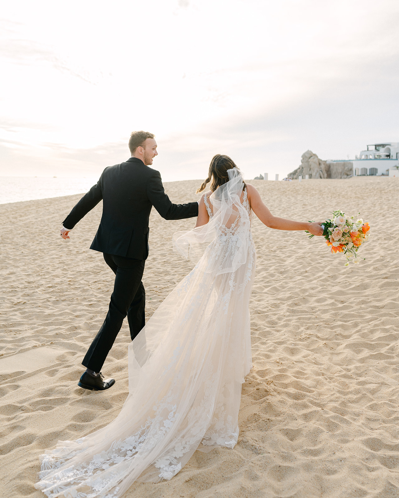Bride and groom walking on the beach after their intimate ceremony in Cabo San Lucas. 