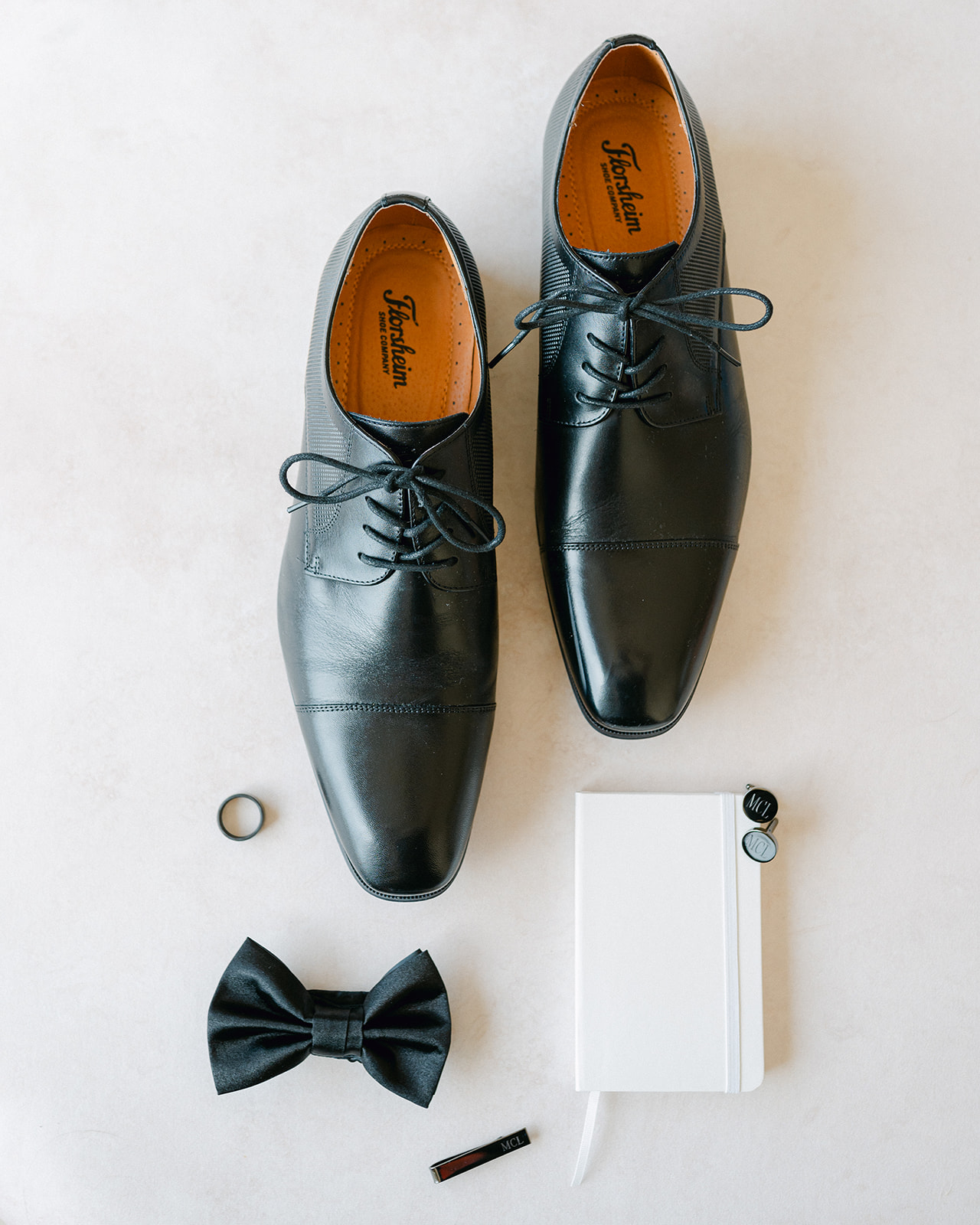 Groom wedding detail flat lay with shoes, vow book, bowtie and accessories. 