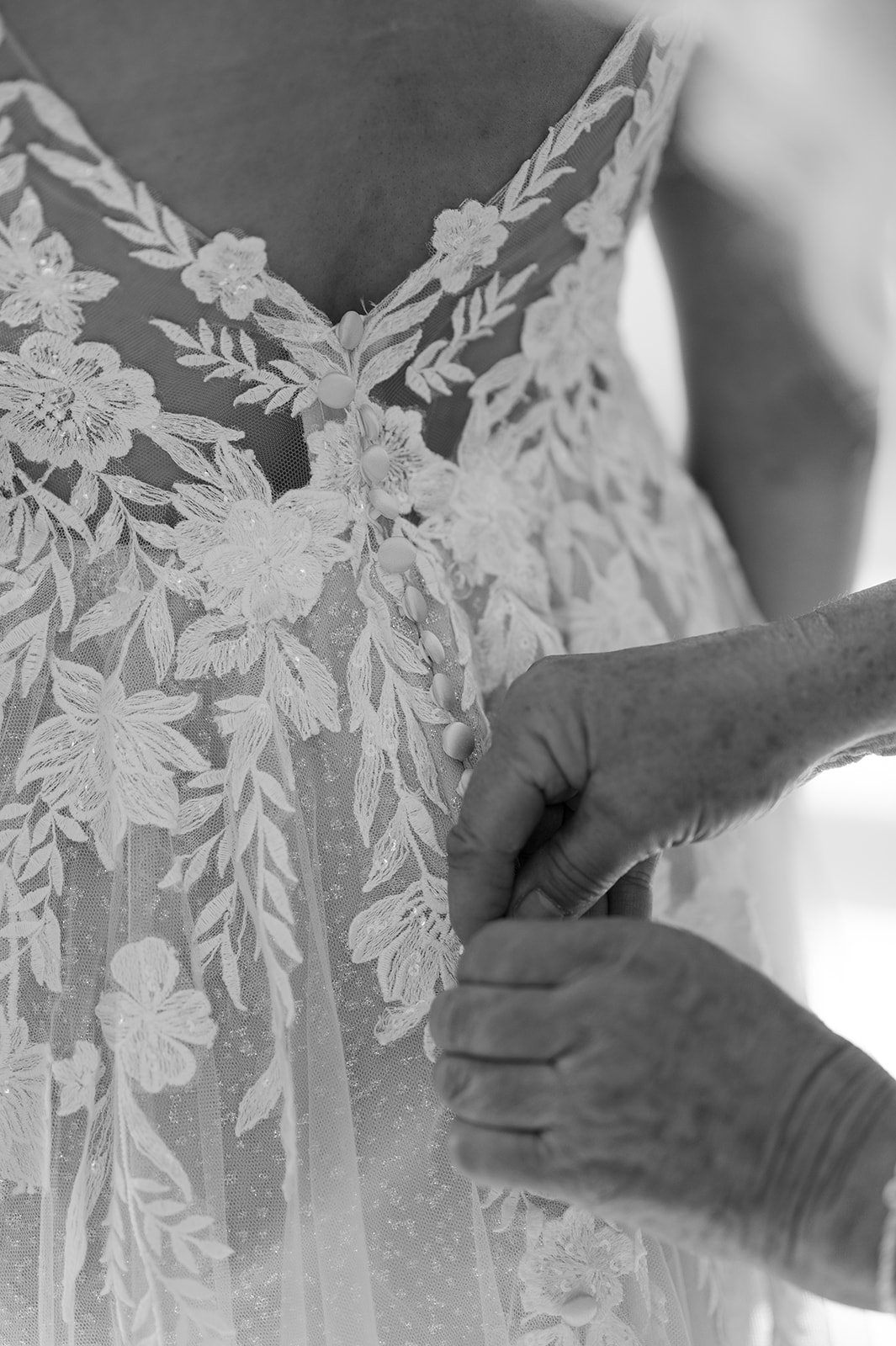 Bride getting her wedding dress buttoned by her grandma. 
