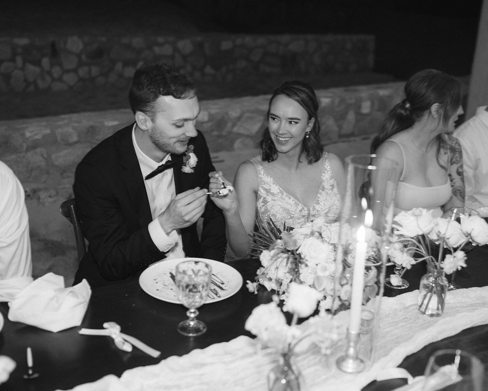 Bride and groom sharing a candid moment during their plated meal on the beach. 