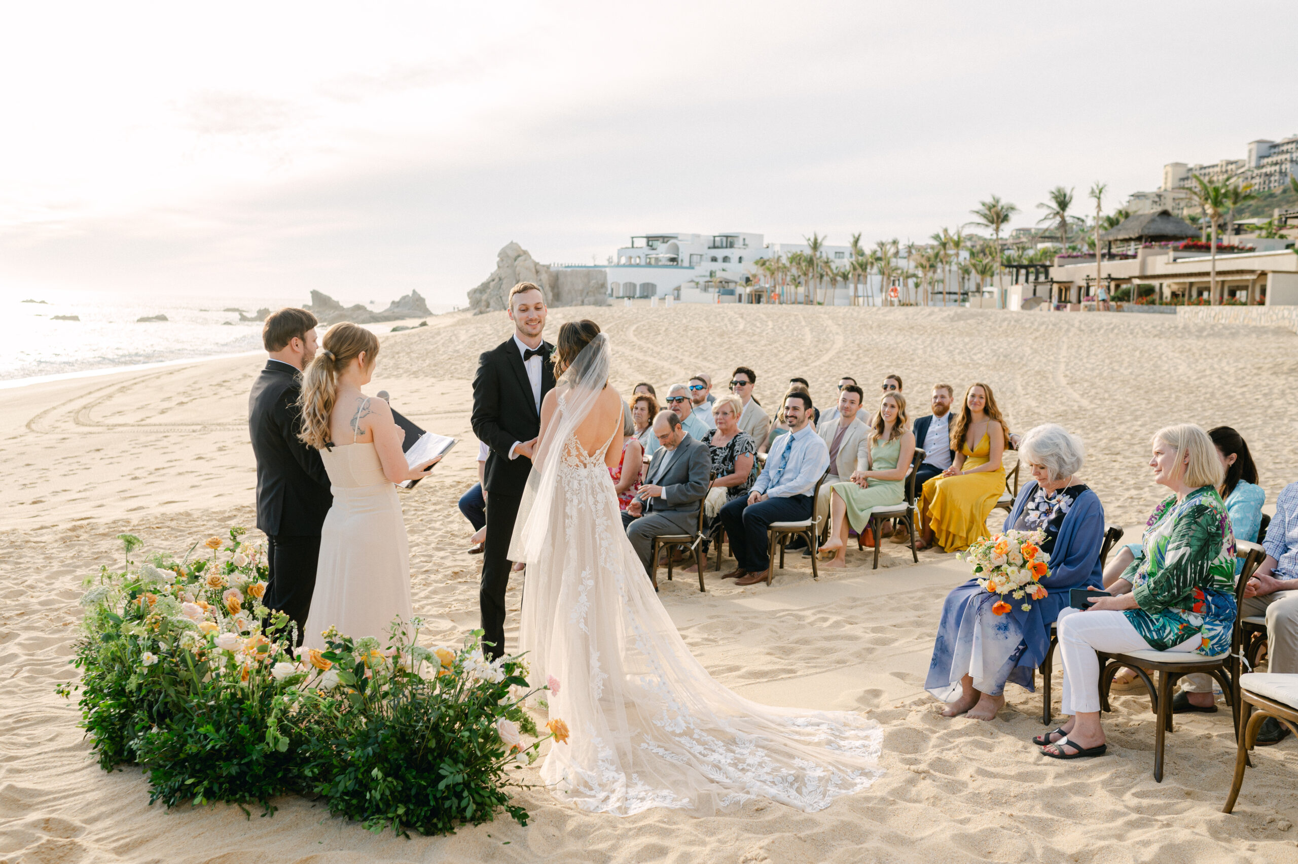 Intimate beach wedding ceremony in Pedregal, Cabo San Lucas with a grounded floral arch. 