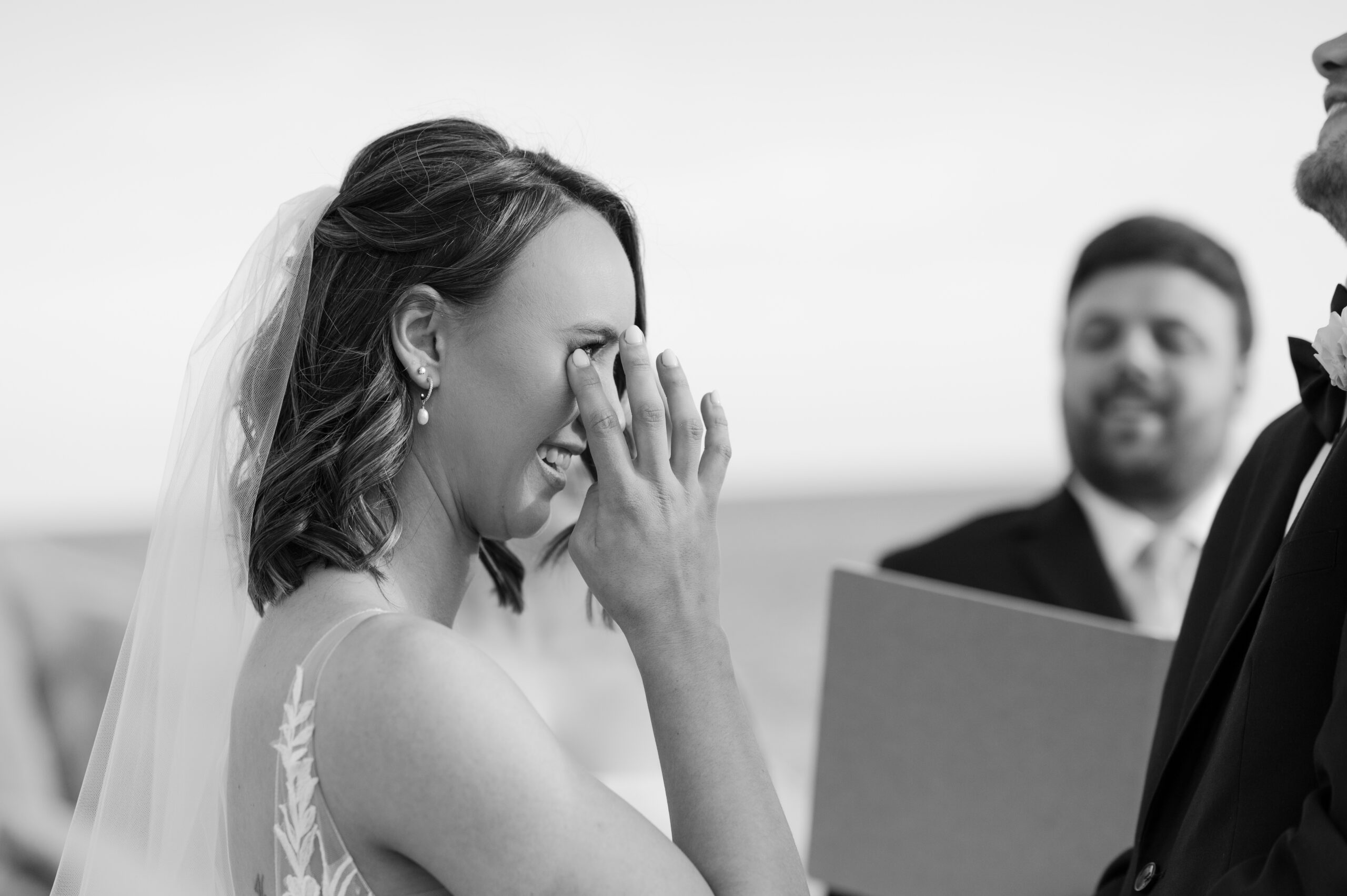 Bride wiping away a tear during her romantic beach wedding ceremony in Mexico.