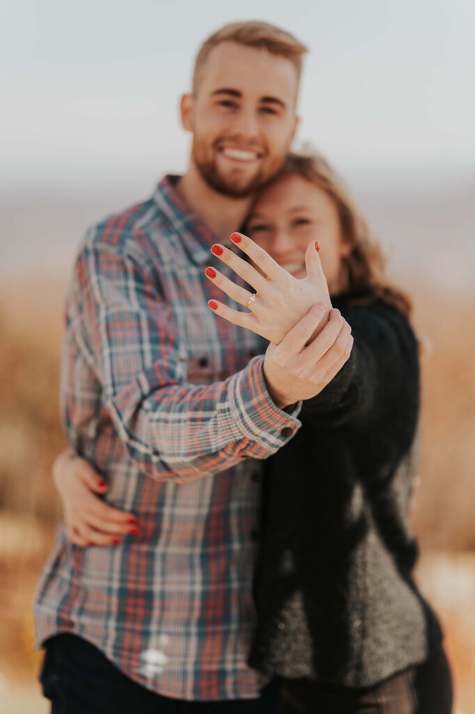 Couple hugs and shows off the woman's engagement ring after their perfect proposal.
