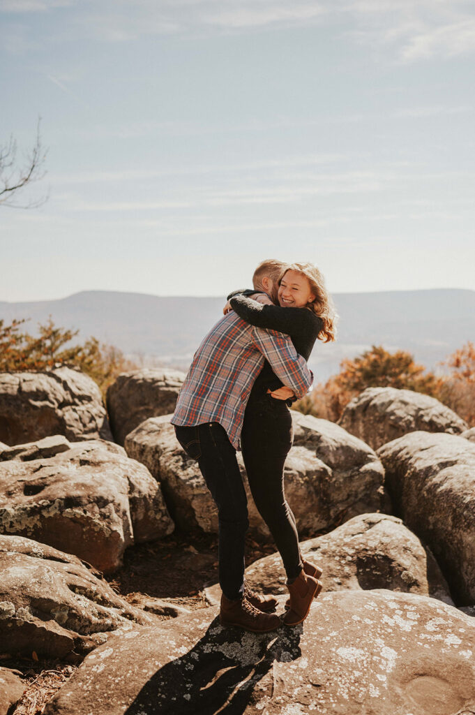 Couple hugs in the mountains after being newly engaged.