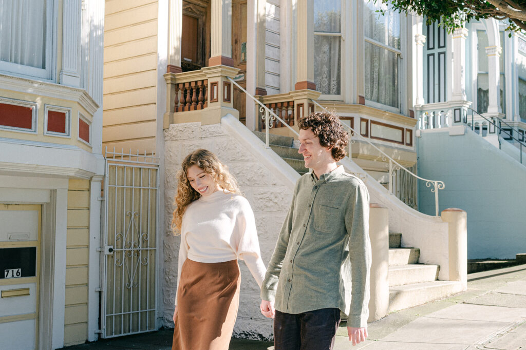 Candid engagement photoshoot in Alamo Square San Francisco with colorful row homes. 