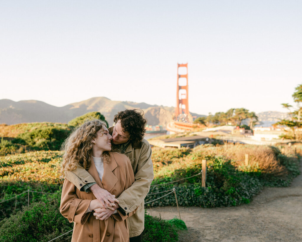 Candid couple leaning in for a kiss at the Golden Gate Overlook in San Francisco. 