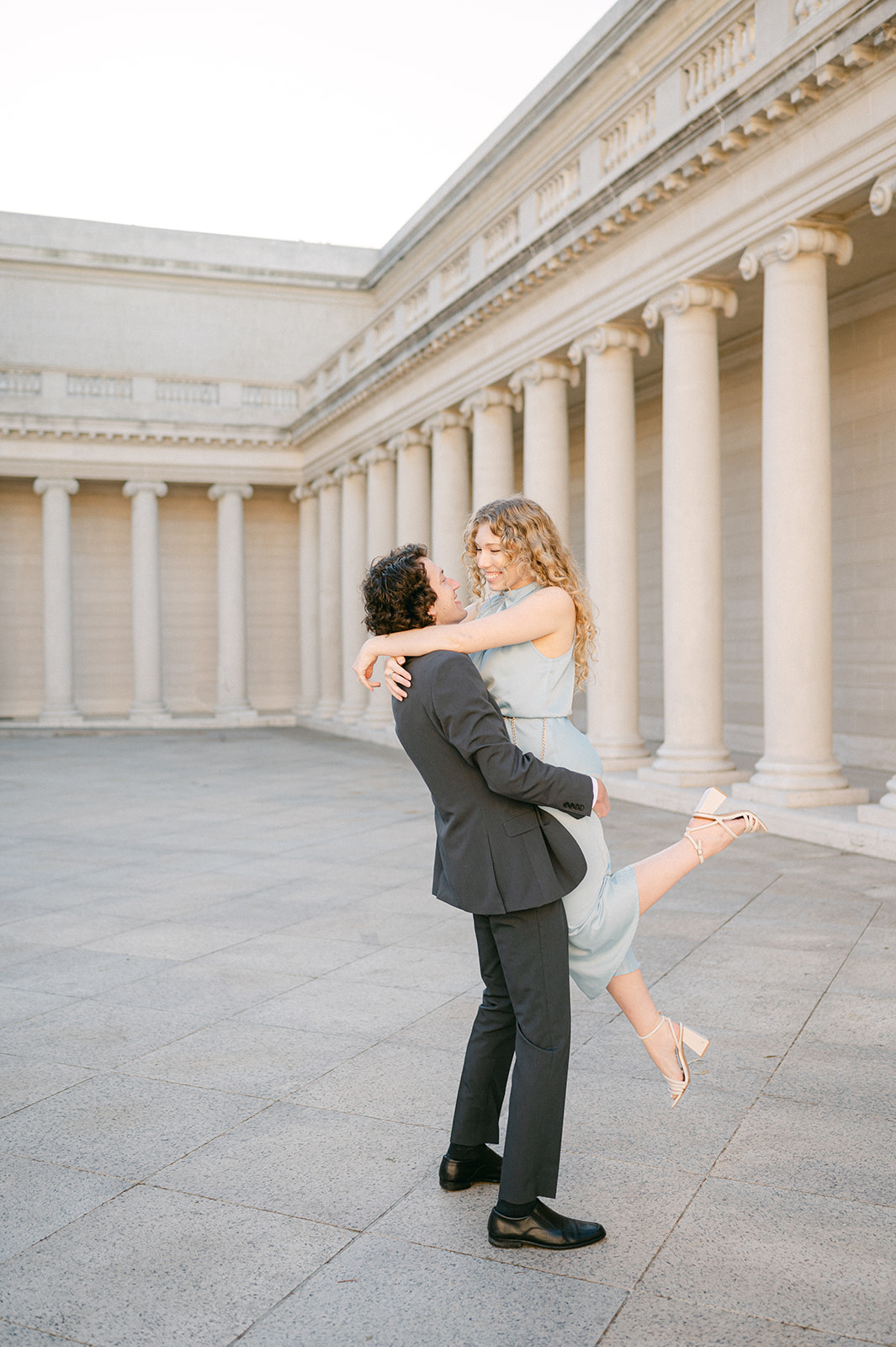 Man lifting up his fiancé at Legion of Honor in San Francisco for their engagement session.