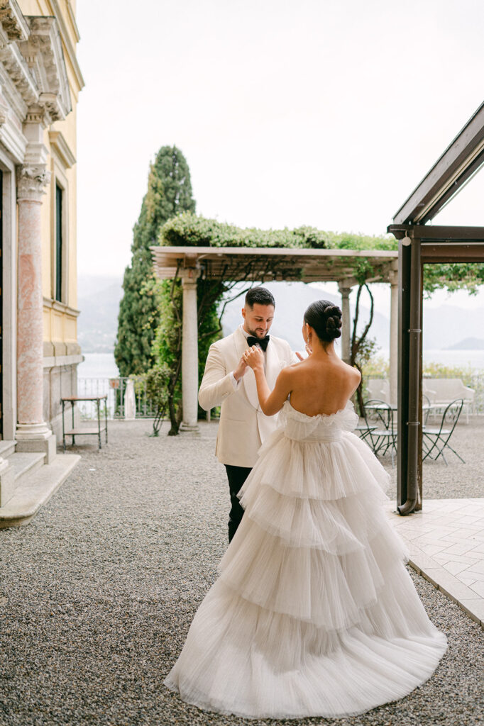 Bride and groom first look on a gravel terrace at Hotel Villa Cipressi. 