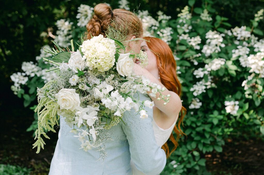 Intimate portrait of the bride and groom in their garden wedding, with the bride's white floral bouquet adding elegance to their kiss.