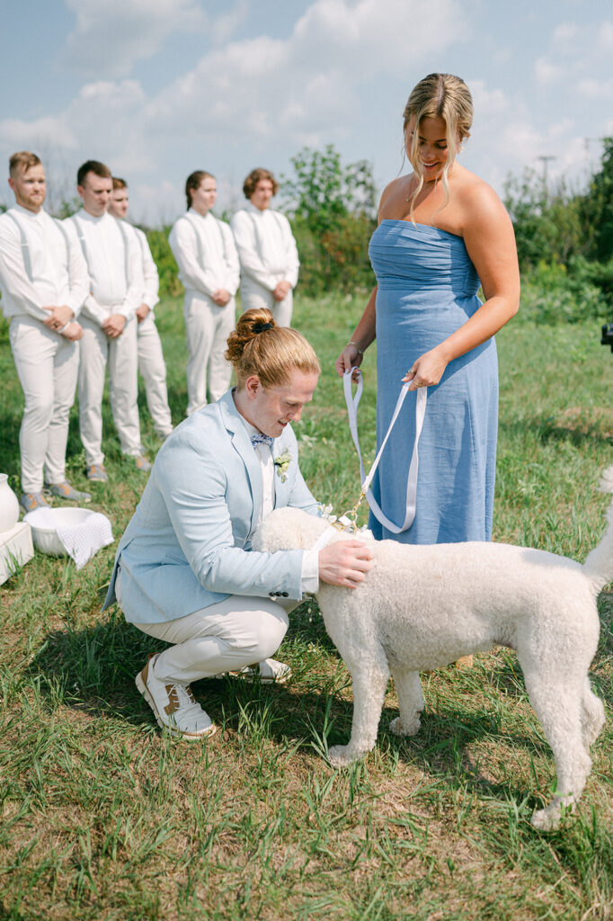 Groom greeting his dog after walking down the aisle with a bridesmaid. 