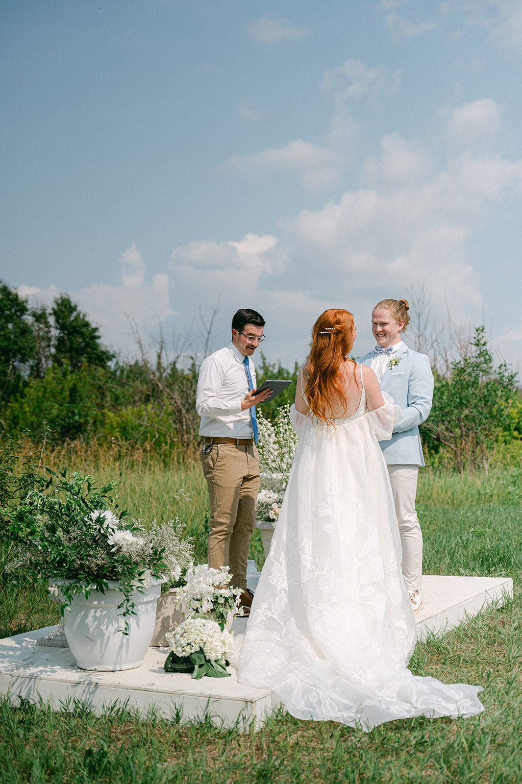 Outdoor wedding ceremony with a groom in a blue suit jacket. 