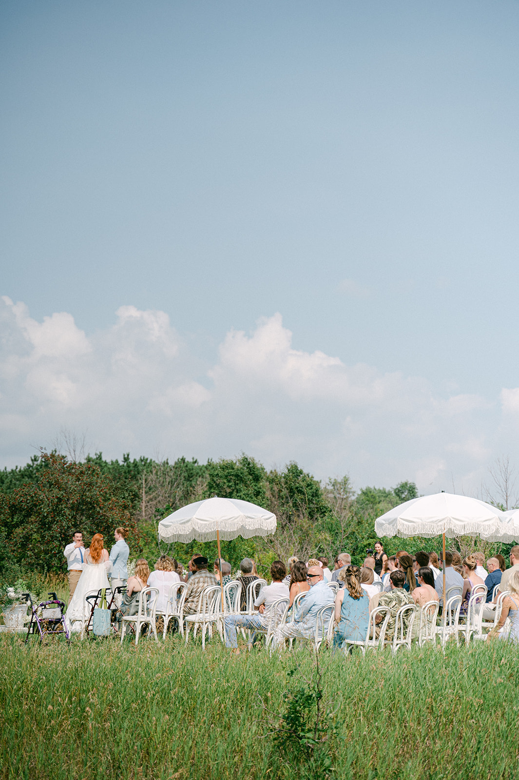 Wide view of an outdoor wedding ceremony in an open field in Battle Lake, MN. 