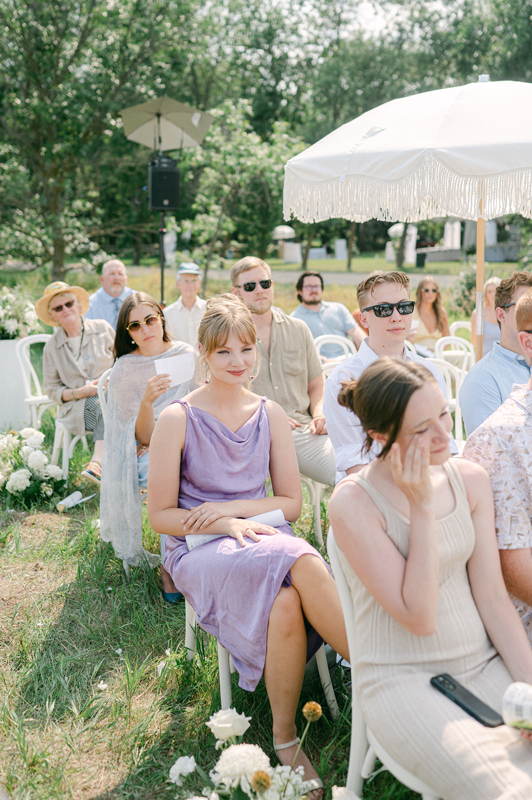 Candid wedding guest portrait during an outdoor ceremony. 