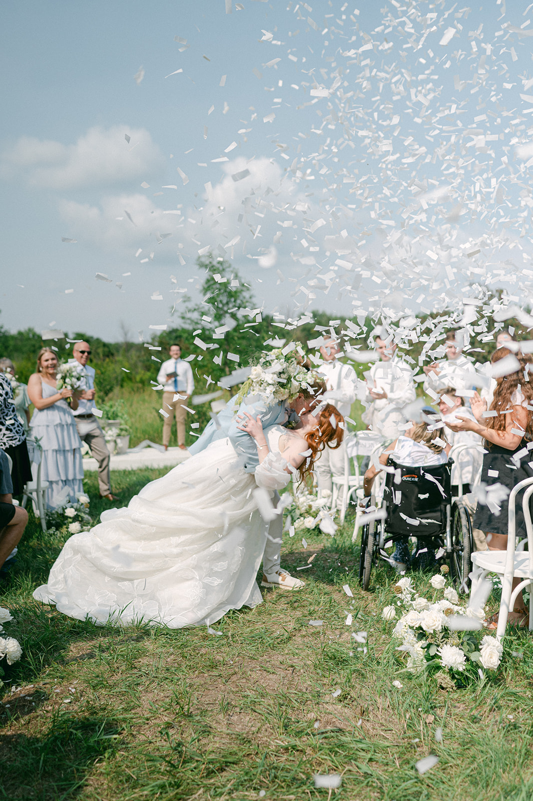 Bride and groom recessional kiss with biodegradable white confetti cannons.