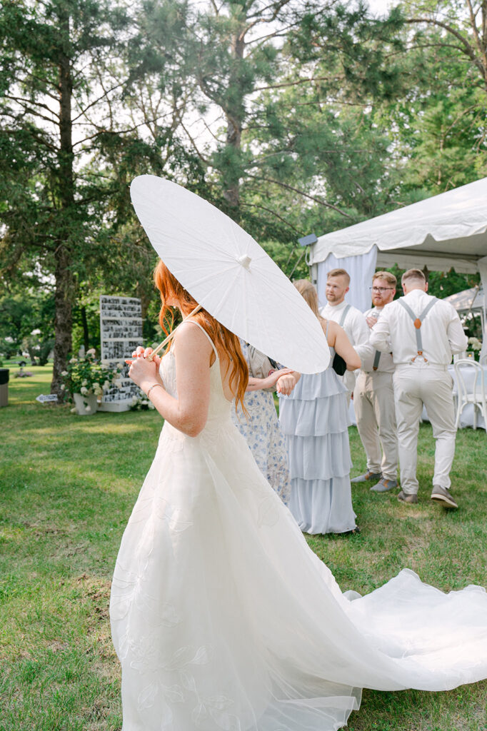 Bride holding her parasol umbrella at cocktail hour. 