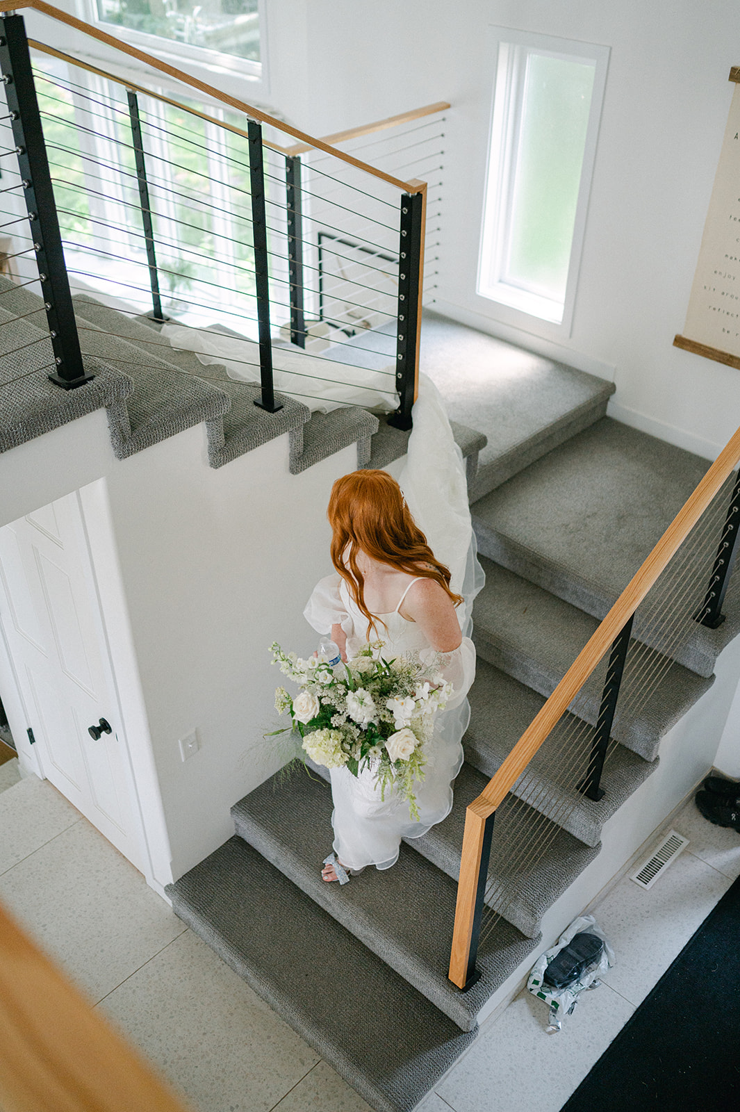 Bird's-eye view of the bride walking down the staircase, moments before her first look with her fiancé.