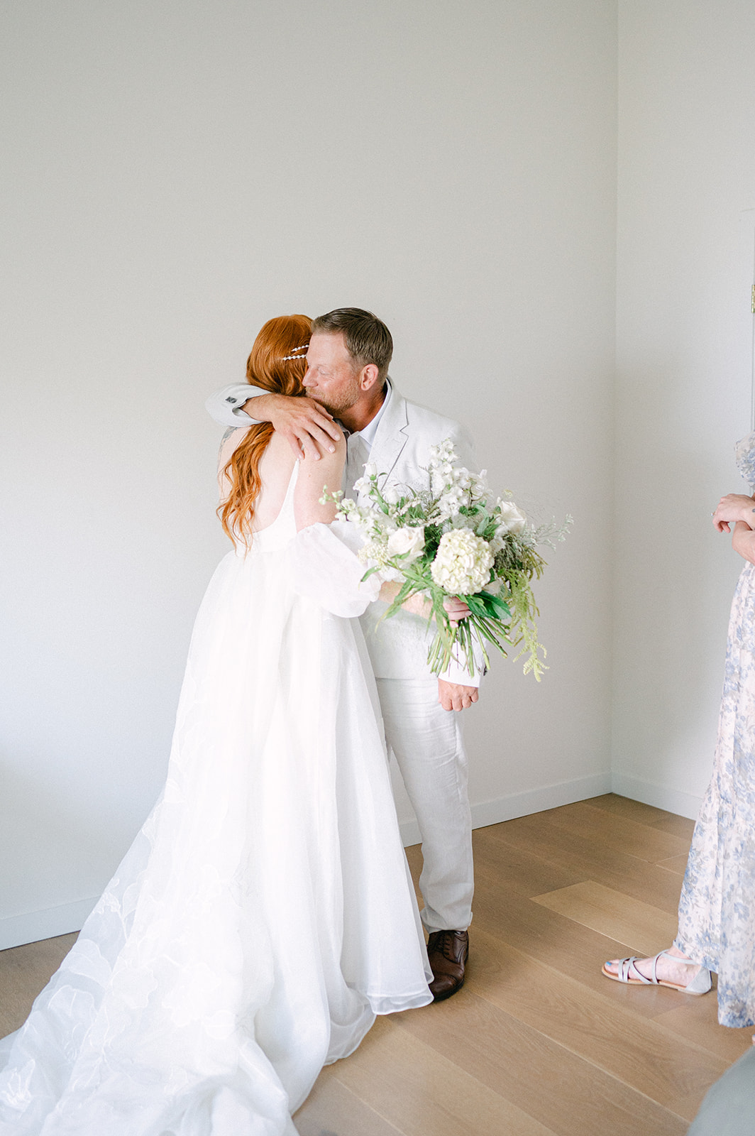 Candid moment of the bride sharing a heartfelt first look with her parents.