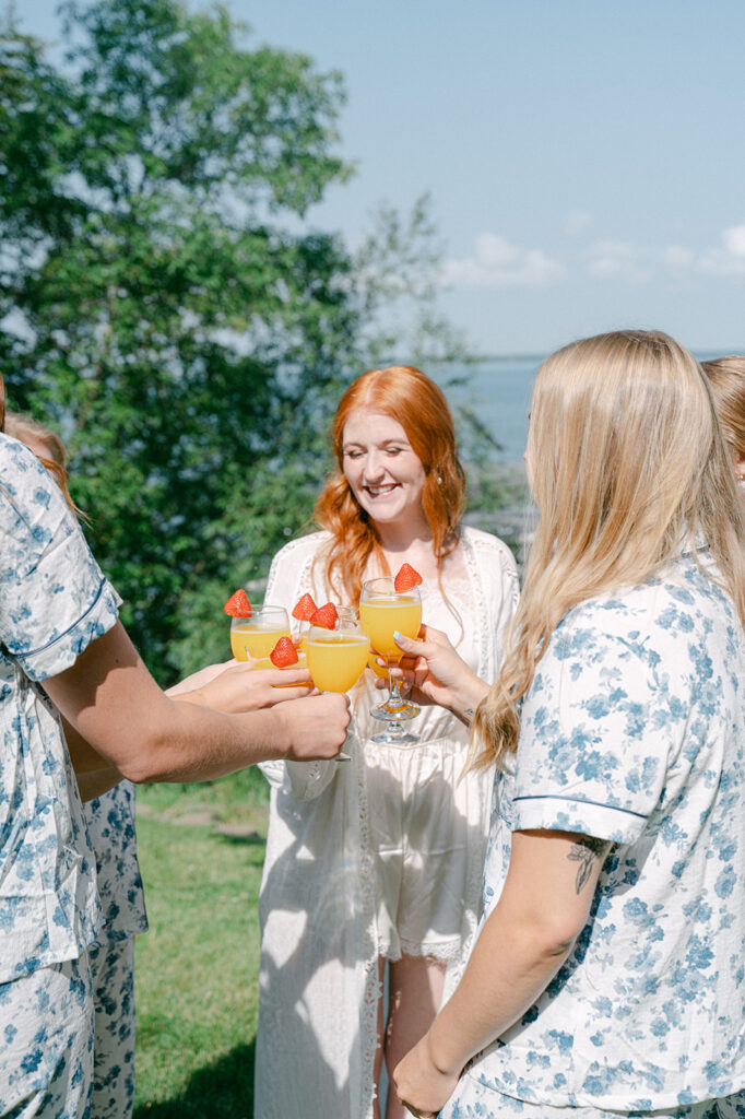 Candid bridal party toasting with mimosas by the lake at a Battle Lake garden wedding.