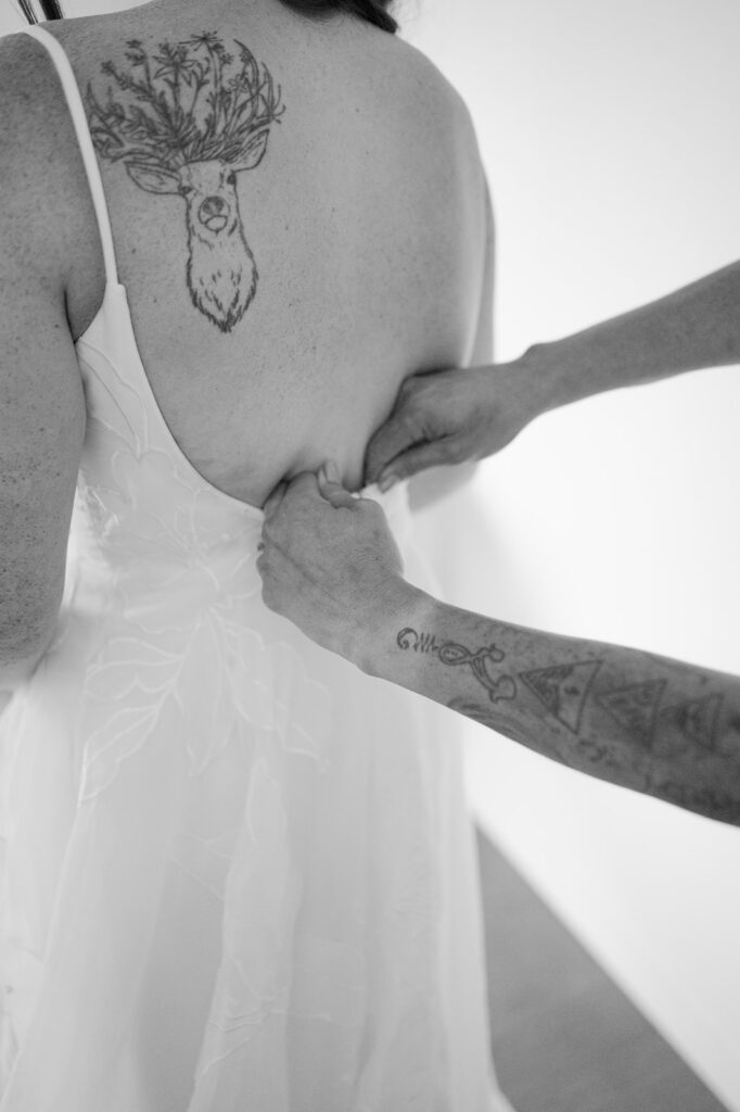 Intimate black and white close-up of the bride's mom carefully zipping up her wedding dress. 