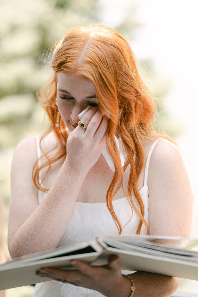 Bride tearing up as she flips through a sentimental photo book from her bridesmaids